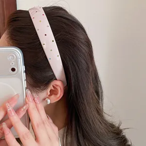 Detailed view of a retro pink acrylic wide headband with colorful rhinestones on model