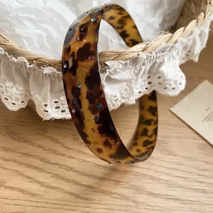 Detail view of a retro tortoise shell acrylic headband with colorful rhinestones