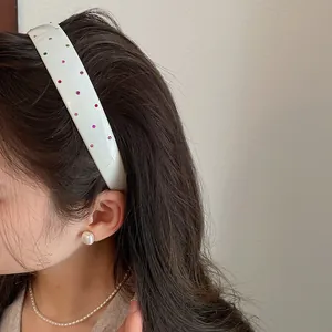 Close-up of white wide acrylic headband with colorful rhinestones on female model