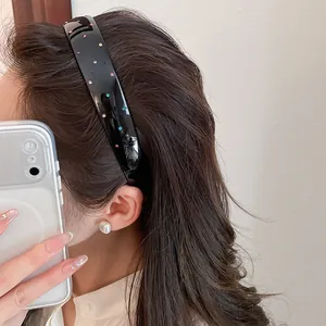 Close-up detail of a vintage black acrylic headband with colorful sparkling rhinestones