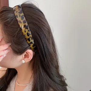 Side view of a vintage leopard print acrylic headband with colorful rhinestones on a model.