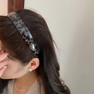 Detail view of a leopard print acrylic headband with colorful rhinestones on a model