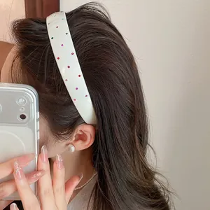 Detail view of a white acrylic wide headband decorated with colorful sparkling rhinestones