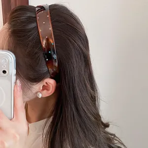 Detail of vintage brown acrylic wide headband with colorful rhinestones on wavy hair