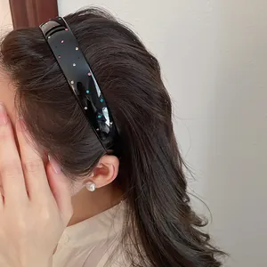 Detail view of a black acrylic headband decorated with vibrant multi-colored rhinestones