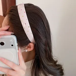 Close-up of pink acrylic headband with colorful rhinestones worn on brown hair