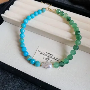 Detailed view of dopamine style necklace with green and blue beads and a central pearl.