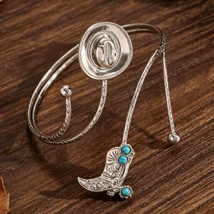 Detailweergave van de zilveren cowboy-armring met turquoise laars en hoed bedeltjes.