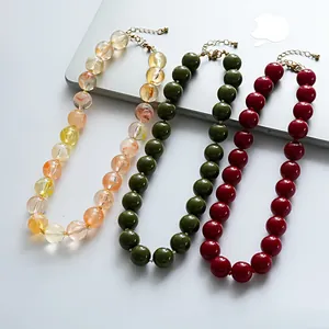 Vue détaillée des colliers en perles d'acrylique marbrées orange, vert et rouge.