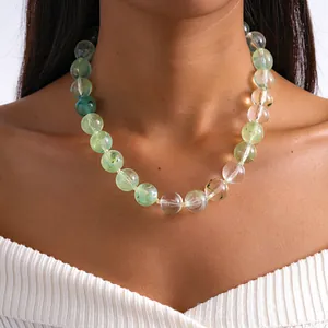 Vue détaillée d'un grand collier de perles en acrylique vert marbré porté par un mannequin