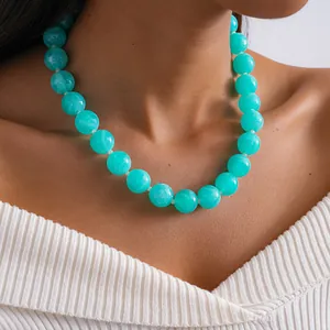 Gros plan d'un collier de perles en acrylique marbré turquoise sur un mannequin.