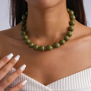 Vue détaillée d'un élégant collier de grosses perles en acrylique vert olive sur un mannequin