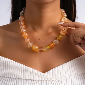 Vue détaillée d'un collier audacieux en perles d'acrylique marbrées orange sur un mannequin.