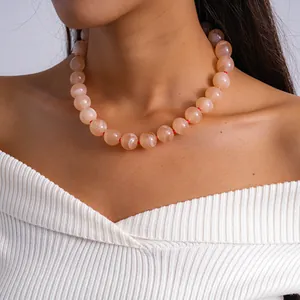 Détail d'un collier élégant avec des perles en acrylique marbrées couleur pêche