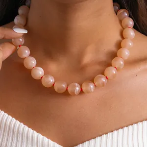 Gros plan d'un collier en acrylique avec perles marbrées et nœuds rouges