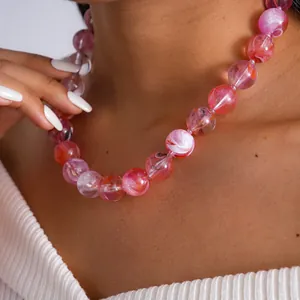Détail macro d'un collier de perles en acrylique rose marbré sur un mannequin