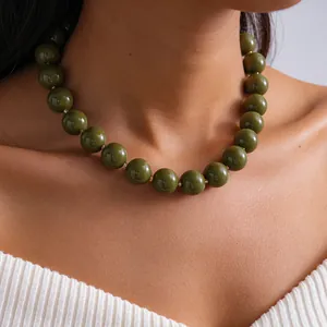 Vue détaillée d'un collier à billes en acrylique vert olive marbré exagéré sur un mannequin.