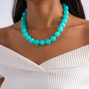 Gros plan d'un collier en perles acryliques turquoise audacieux sur un mannequin