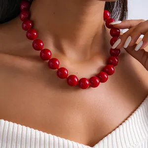 Vue rapprochée d'un collier en perles d'acrylique rouge vif porté par un mannequin