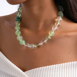 Détail d'un collier de perles en acrylique marbré vert sur un mannequin en haut blanc