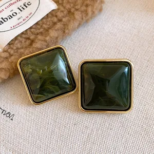 Dettaglio di orecchini quadrati in acrilico marmorizzato verde scuro con cornice d'oro