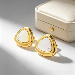 Nahaufnahme goldener Dreiecksohrringe mit weißer Muscheleinlage und Zirkonia-Akzent.