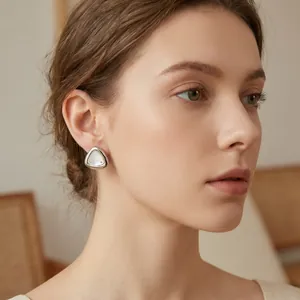 Detailansicht eines eleganten Dreieck-Ohrrings aus Edelstahl mit Muscheleinlage am Modell