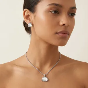 Nahaufnahme eines minimalistischen Schmucksets aus Edelstahl mit Muscheleinlagen am Modell