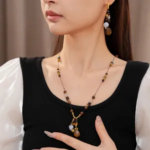 Detail view of ethnic vintage wooden beaded necklace and waterdrop earrings on model