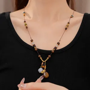 Detail view of an ethnic style necklace with wooden beads and resin water drop pendant.