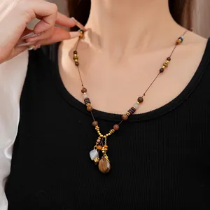 Close-up of ethnic vintage beaded necklace with wood resin teardrop pendant on model