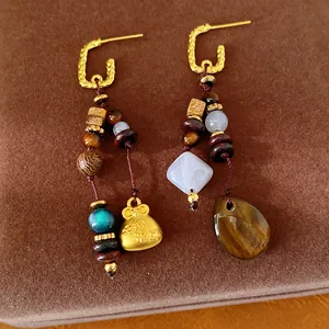 Detailed view of ethnic retro earrings featuring wooden beads and a golden lucky bag charm