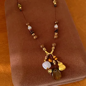 Detailed view of ethnic style necklace featuring wooden beads and golden lucky bag charm.