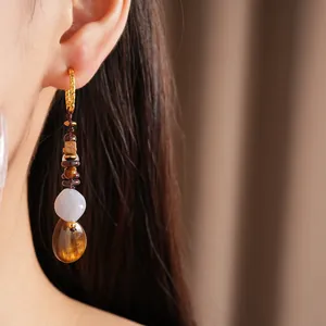 Close-up of vintage ethnic earring featuring wood beads and amber resin teardrop pendant