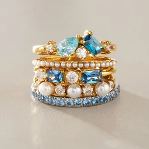 Detailed macro shot of stacked stainless steel rings with blue stones and pearls.