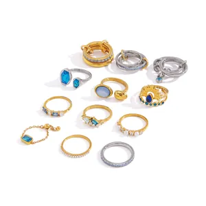 Collection of stainless steel rings with blue zircon and pearls in gold and silver tones.