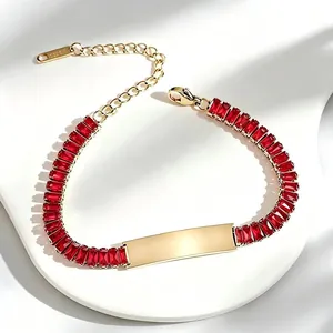 Close-up of gold-plated stainless steel bracelet with red rectangular zircons and engravable bar.