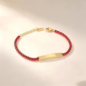 Detailed view of gold stainless steel bracelet with red stones and engraving plate.