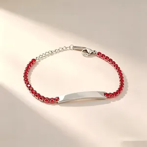 Detail view of a stainless steel bracelet with red zircons and an engravable bar.