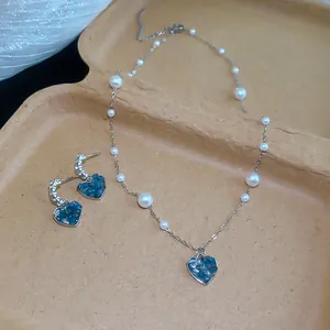 Gros plan d'un ensemble élégant collier et boucles d'oreilles cœur en verre bleu