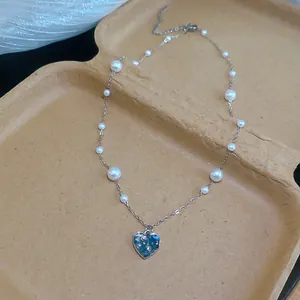 Gros plan d'un collier cœur vintage avec du zircon bleu et d'élégantes perles blanches.