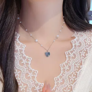 Collier vintage élégant avec pendentif cœur bleu et perles porté par un modèle.