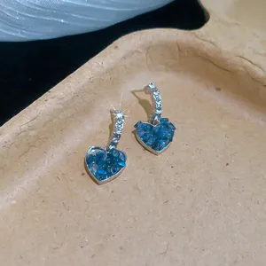 Vue détaillée des boucles d'oreilles cœur bleu vintage avec zircons sur plateau beige