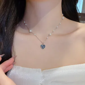 Vue détaillée d'un élégant collier cœur en argent avec zircon et perles sur un modèle.