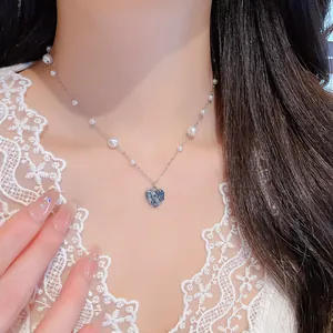 Vue détaillée d'un collier cœur en zircon bleu avec perles élégantes sur un mannequin