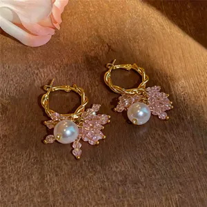 Macro view of gold hoop earrings featuring elegant pearls and pink crystal beads.