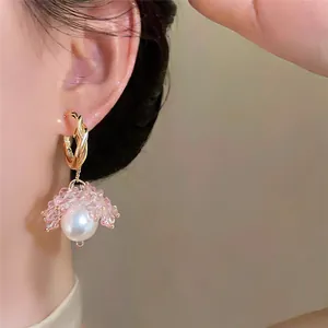 Detailed view of elegant pearl earrings featuring pink floral beads on a golden hoop.