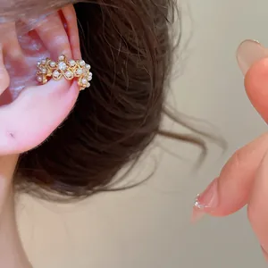 Vue détaillée d'un ear cuff plaqué or 18 carats avec perles et fleurs en zircone.