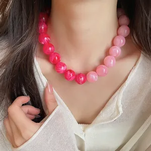 Close-up detail of a pink dopamine acrylic marbled beaded necklace on a model's neck