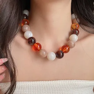 Close-up of colorful acrylic beaded necklace with dopamine style amber and cream tones